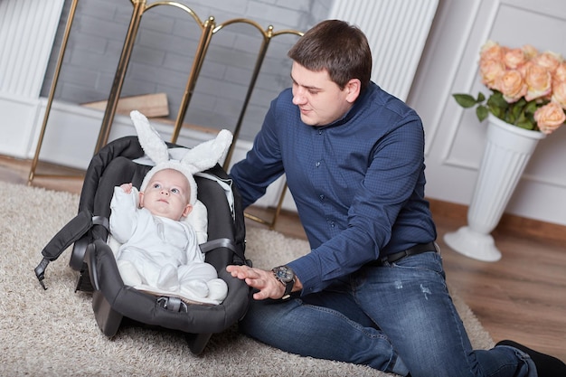 Liebevoller Papa und ein hübsches Baby im Hasenkostüm vor einem Spaziergang