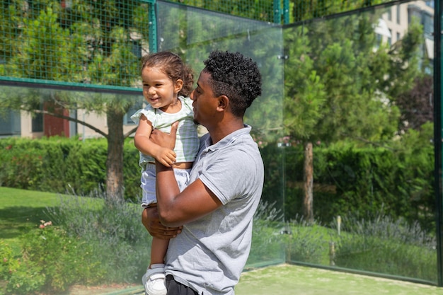 Liebevoller schwarzer Vater mit süßer Tochter auf Sportplatz