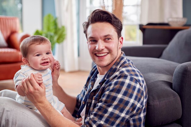 Liebevoller Transgender-Vater, der mit dem kleinen Sohn spielt, der zu Hause auf dem Boden sitzt