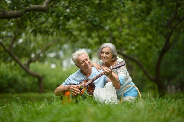 Liebevolles älteres Paar mit Gitarre im Sommerpark