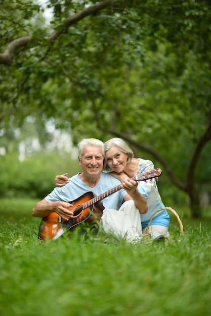 Liebevolles älteres Paar mit Gitarre im Sommerpark