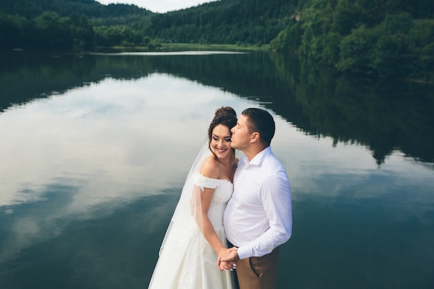 Liebevolles Hochzeitspaar, das in den Bergen umarmt