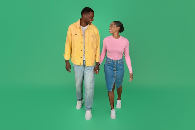 Liebevolles junges afroamerikanisches Paar, das über grünen Hintergrund läuft