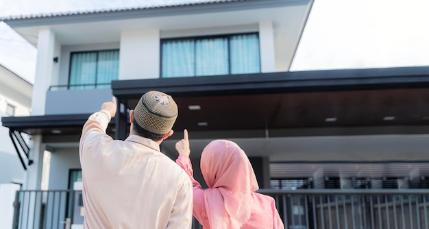 Liebevolles junges Paar, das sich das Traumhaus ansieht Porträt eines aufgeregten muslimischen Paares, das vor seinem neuen Zuhause steht und auf dem neuen Modellhaus spazieren geht