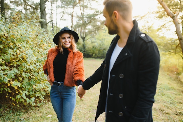 Liebhaber gehen Hand in Hand im Herbstpark