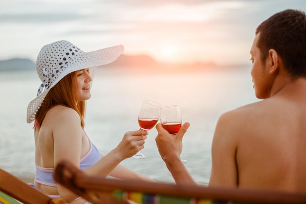 Liebhaber klirren mit dem breiten Glas am Strand. Genießen Sie den sonnigen Tag am tropischen Strand.