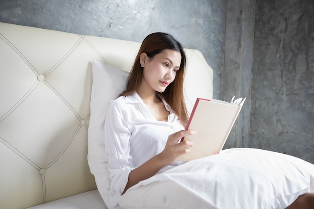 Lieblingsbuch der asiatischen Frauen Lesebuch am weißen Schlafzimmer schoss auf erstaunlicher Zeit, um sich zu entspannen