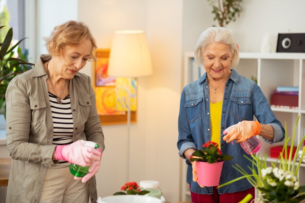 Lieblingshobby. Positive, gut aussehende Frauen, die lächeln, während sie die Gartenarbeit genießen