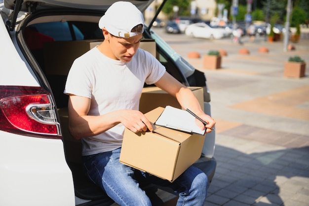 Lieferbote, der Box vom Auto abholt.