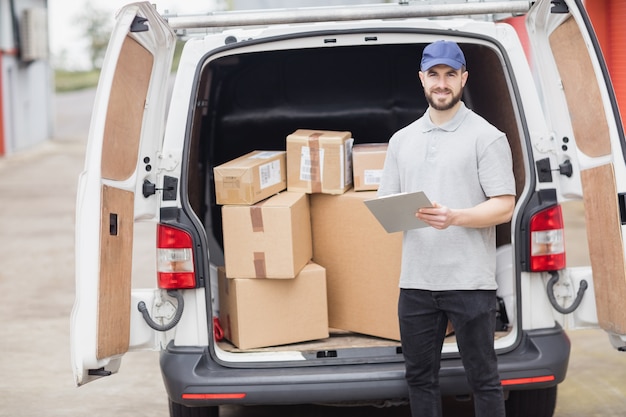 Lieferbote, der Klemmbrett vor seinem Packwagen hält