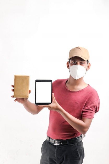 Lieferbote, der medizinische Maske trägt und Smartphone-Bildschirm mit Box in den Händen zeigt. Hauslieferung. Online-Technologie bestellen.