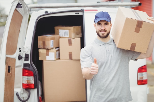 Lieferbote, der Paket vor seinem Packwagen hält