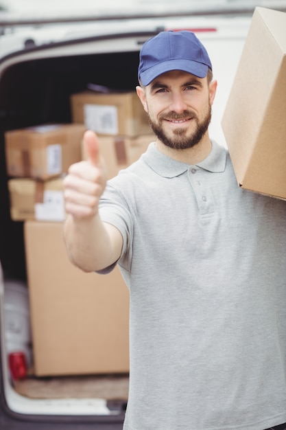 Lieferbote, der Paket vor seinem Packwagen hält