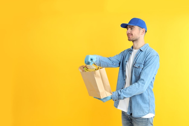 Lieferbote hält Tasche mit Essen auf gelbem Hintergrund