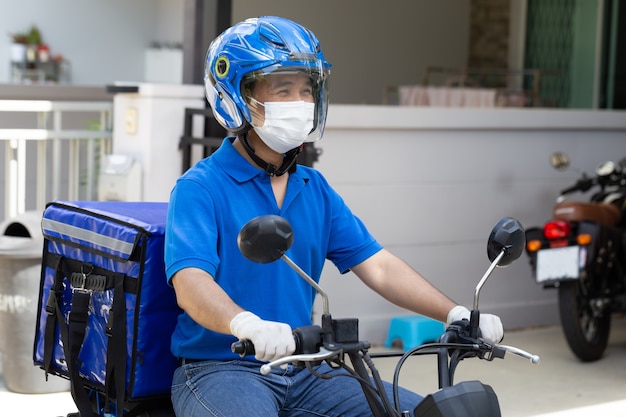 Lieferbote in blauer Uniform mit Motorrad und Lieferbox