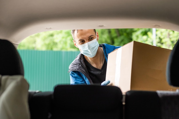 lieferbote in einer medizinischen maske und handschuhen liefert das paket. Quarantäne, Coronavirus, Isolation.