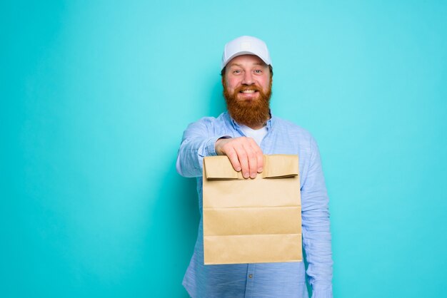 Lieferbote mit glücklichem Gesichtsausdruck ist bereit, ein Lebensmittelpaket zu liefern