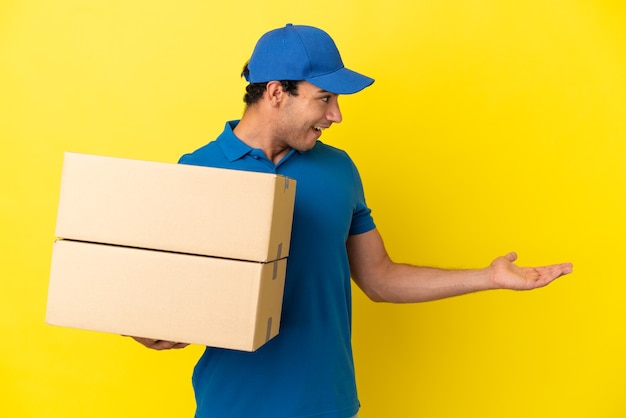 Lieferbote über isolierter gelber Wand mit Überraschungsausdruck beim Blick auf die Seite