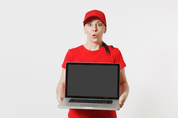 Lieferkonzept. Frau in roter Mütze, T-Shirt isoliert auf weißem Hintergrund. Professionelle kaukasische Frau, die als Kurier arbeitet und PC-Computer mit leerem leerem Bildschirm hält, um Platz für Werbung zu kopieren.