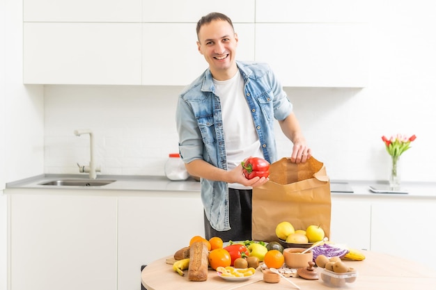 Lieferkonzept - Gutaussehender cacasianischer Lieferbote, der eine Paketbox mit Lebensmitteln und Getränken aus dem Laden trägt. Platz kopieren..