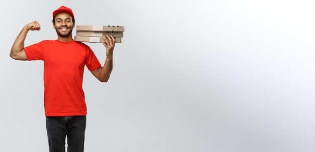 Lieferkonzept Porträt eines starken afroamerikanischen Liefermanns, der seinen Muskel mit Pizzakartonpaketen zeigt, die auf grauem Studio-Hintergrund-Kopienraum isoliert sind