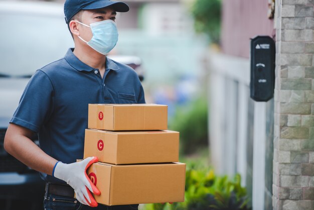 Lieferpersonal mit Papierboxen. Tragen Sie medizinische Handschuhe und Masken, um Covid-19 zu schützen