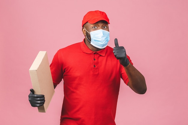 Lieferung Afroamerikaner Mann Mitarbeiter in roter Kappe leer T-Shirt Uniform Gesichtsmaske Handschuhe halten leere Pappschachtel