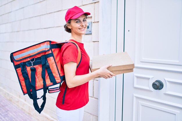 Foto lieferung business worker frau in uniform lächelnd glücklich an die tür klopfen