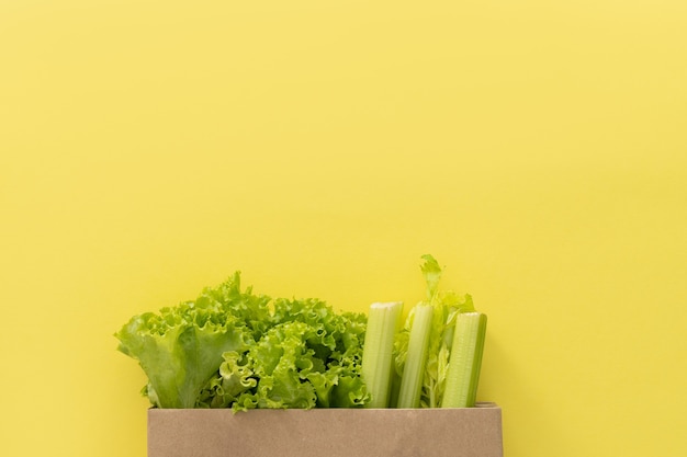 Lieferung gesunder Lebensmittelhintergrund. Veganes vegetarisches Essen in Papiertütengemüse auf gelbem Hintergrund. Lebensmittelsupermarkt und sauberes Essenskonzept