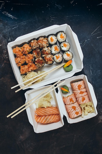 Lieferung in Kartons mit Sushi-Rollen auf dunklem Hintergrund