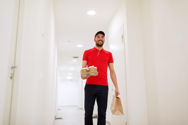 Foto lieferung, post und menschenkonzept - happy man liefert kaffee und lebensmittel in einwegpapiertüten an kunden zu hause