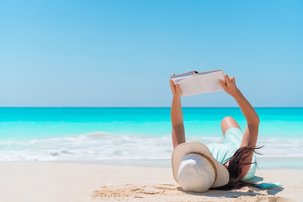 Liegender tropischer weißer Strand des Buches der jungen Frau Lese