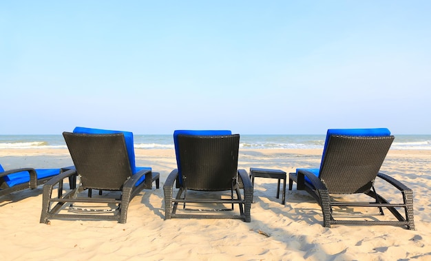 Liegestühle am Sandstrand am bewölkten blauen Himmel und sonnig