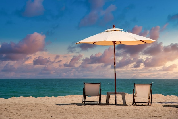 Liegestühle am Sandstrand mit dramatischem Himmel bei Sonnenuntergang