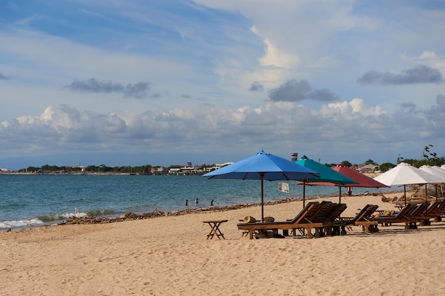 Liegestühle mit Sonnenschirmen an einem Sandstrand in der Meeresbucht