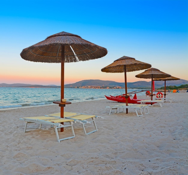 Liegestühle und Sonnenschirme in Alghero im Morgengrauen