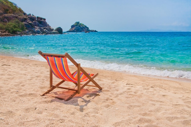 Liegestuhl am Strand mit Felsen im Hintergrund