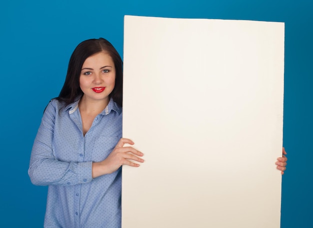 El lienzo blanco está en manos de una mujer con labios rojos contra un fondo azul.