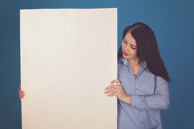 El lienzo en blanco está en manos de una mujer con labios rojos contra un fondo azul.