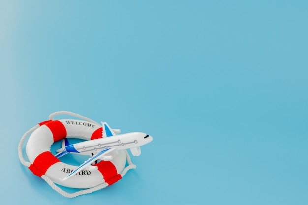 Lifebuoy e modelo de avião sobre fundo azul. Conceito de verão ou férias. Copie o espaço.