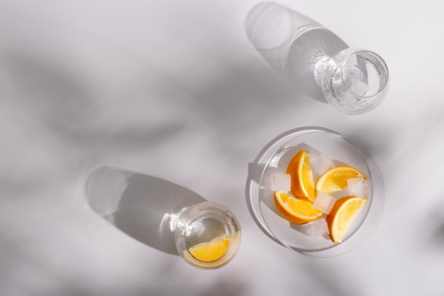 Lifestyle-Foto mit Glasbechern mit frischem kaltem Wasser und Orangenscheibe auf dem Teller
