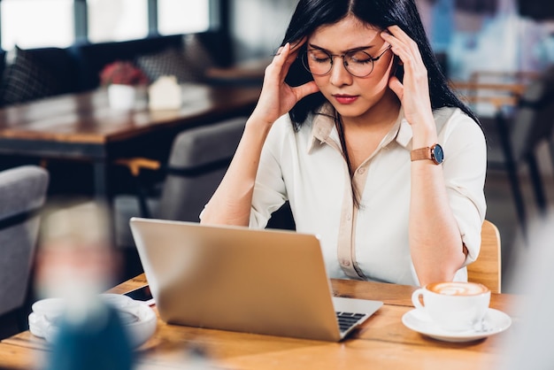 Lifestyle freiberufliche berufstätige Frau und Laptop-Computer er Kopfschmerzen unglücklich bei der Arbeit im Café-Shop