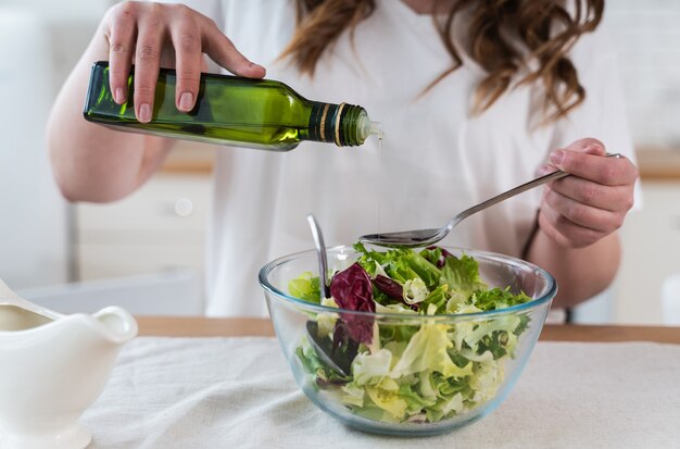 Lifestyle-Momente einer jungen Frau zu Hause. Frau bereitet einen Salat in der Küche zu