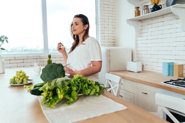 Lifestyle-Momente einer jungen Frau zu Hause. Frau bereitet einen Salat in der Küche zu
