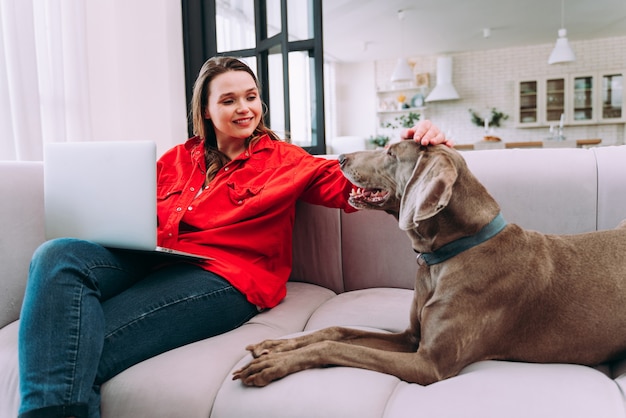 Lifestyle-Momente einer jungen Frau zu Hause. Frau spielt mit ihrem Hund im Wohnzimmer