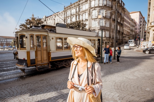 Lifestyle-Porträt einer Frau mit Fotokamera in der Nähe der berühmten alten touristischen Straßenbahn auf der Straße in der Stadt Porto, Portugal
