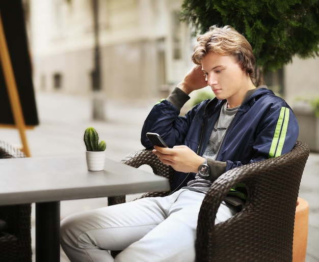Lifestyle-Porträt eines jungen Mannes, der im Freien ein Smartphone nutzt