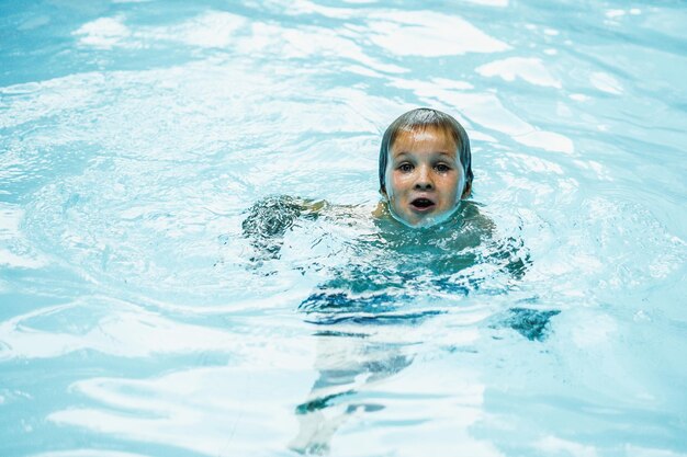 Lifestyle Porträt Junge nur Kopf Blick in die Kamera offener Mund Lächeln Gesichtsausdruck fröhliche Stimmung Schwimmen im Pool Wasser Gesicht Haut nasse Haare Kind Verhalten Erziehung Sohn schwierig Aqua-Schulunterricht