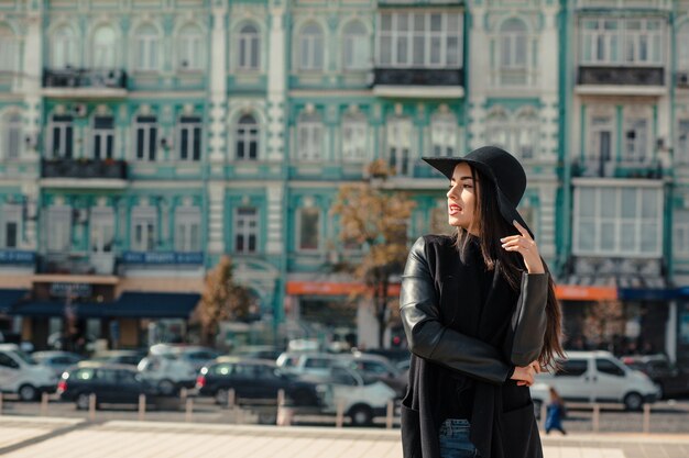 Lifestyle-Porträt von Glamour-Brünette-Modell mit hellem Make-up in modischem Mantel und Hut, die auf der Stadtstraße posieren