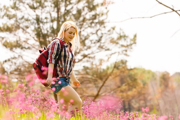 Lifestyle-Sommerbild einer hübschen blonden Hipster-Frau mit Rucksack, die reist und genießt, stilvoller frischer Look, fröhliche Stimmung, sonnige Farben, Reisekonzept, Emotionen.